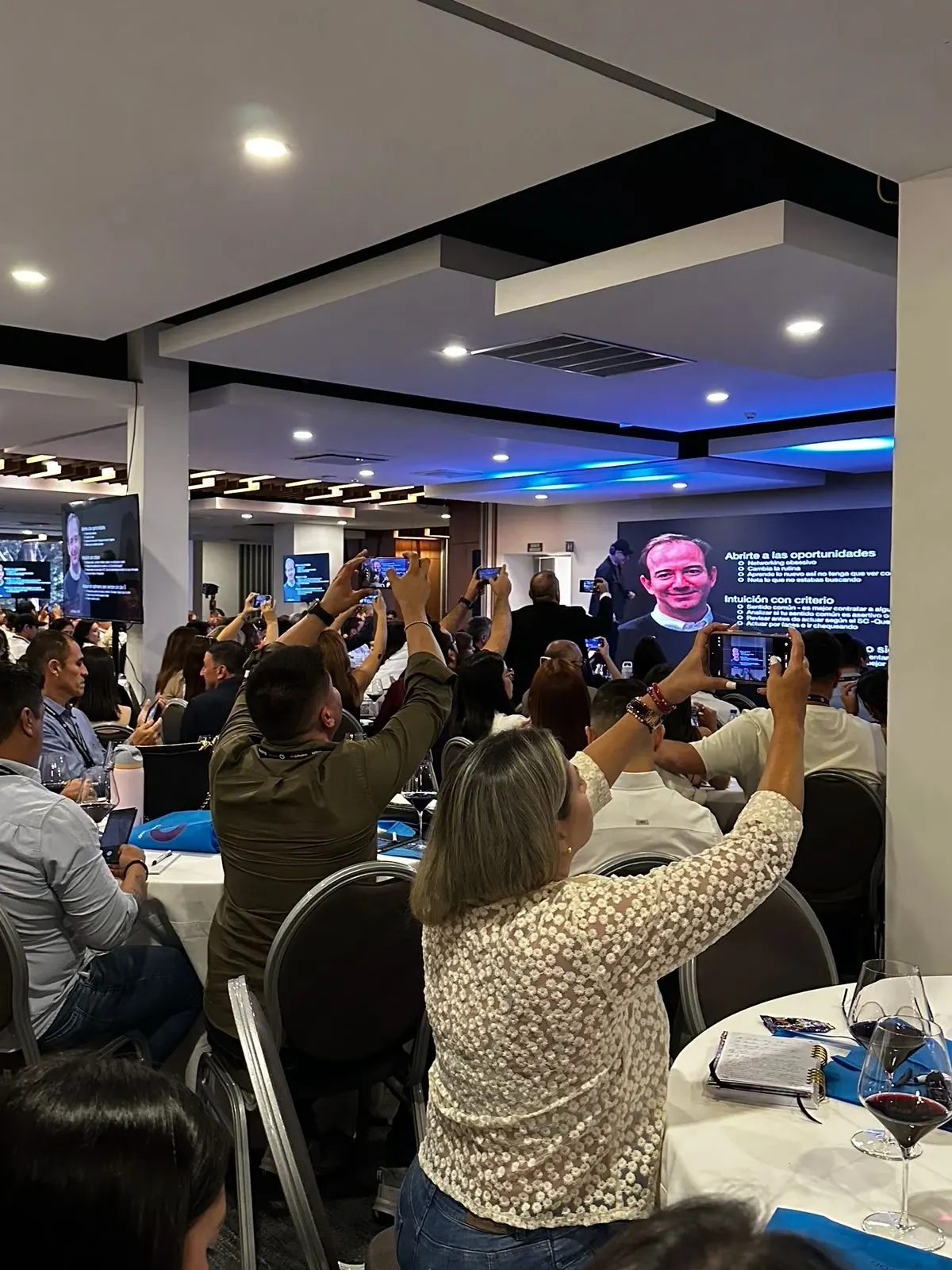Asistentes levantan el celular para fotografiar una diapositiva
