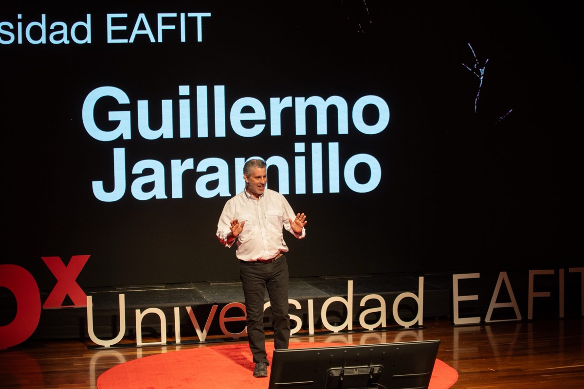 Guillermo en el escenario de TEDx Universidad EAFIT, con su nombre en la pantalla